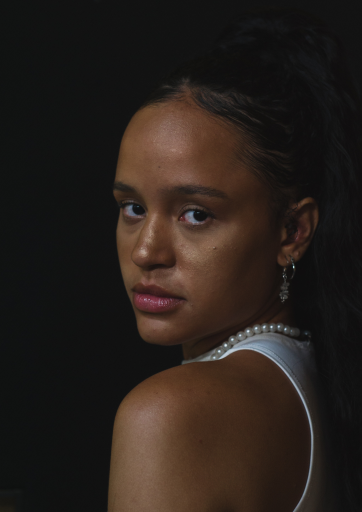 Elegant portrait of a woman with a pearl necklace, looking back over shoulder.